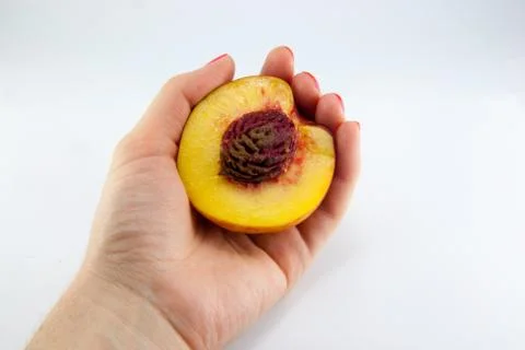 Hand with a fresh juicy peach split in half isolated Stock Photos