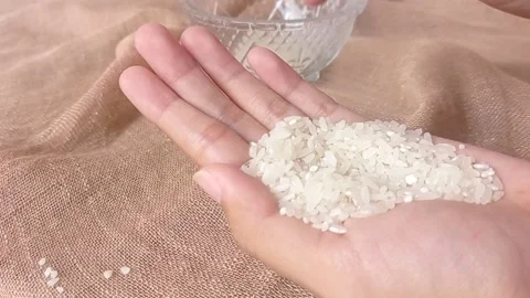 A hand full of rice with a brown background Stock Footage 146255243