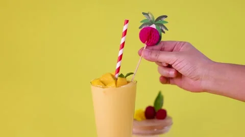 Hand Garnishes Mango Smoothie with Decorative Fruit Topper Stock Footage 321049486
