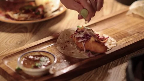 Hand Garnishing Crispy Fish Taco with Lime in Bangkok Eatery 動画素材 313786560