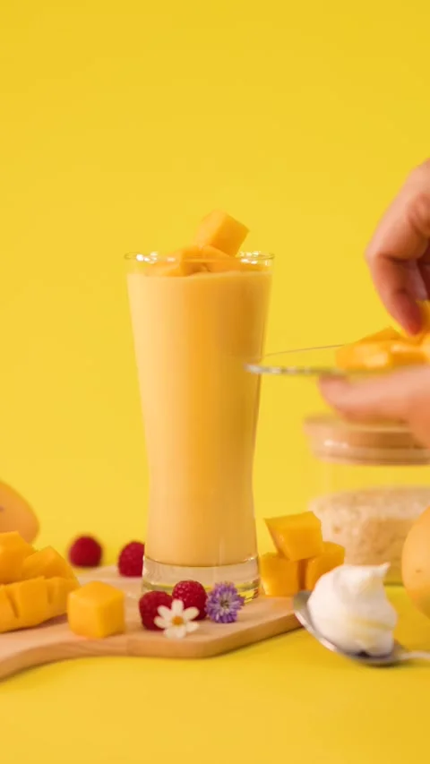 Hand Garnishing Mango Smoothie with Fresh Fruit Cubes 库存影片 323679697