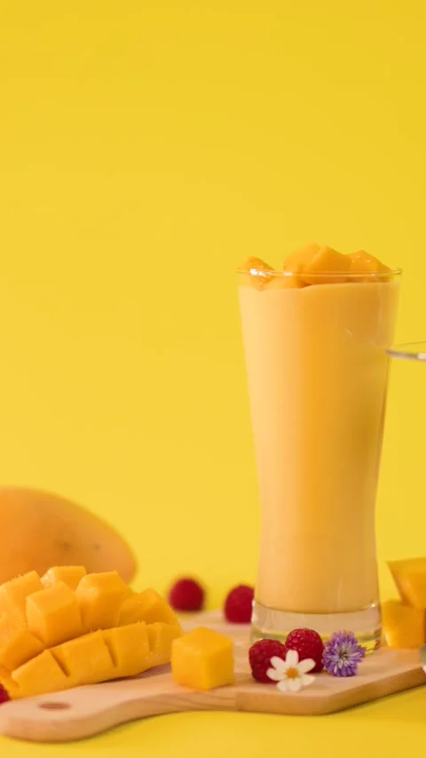 Hand Garnishing Mango Smoothie with Fresh Fruit Cubes Stock Footage 323683214