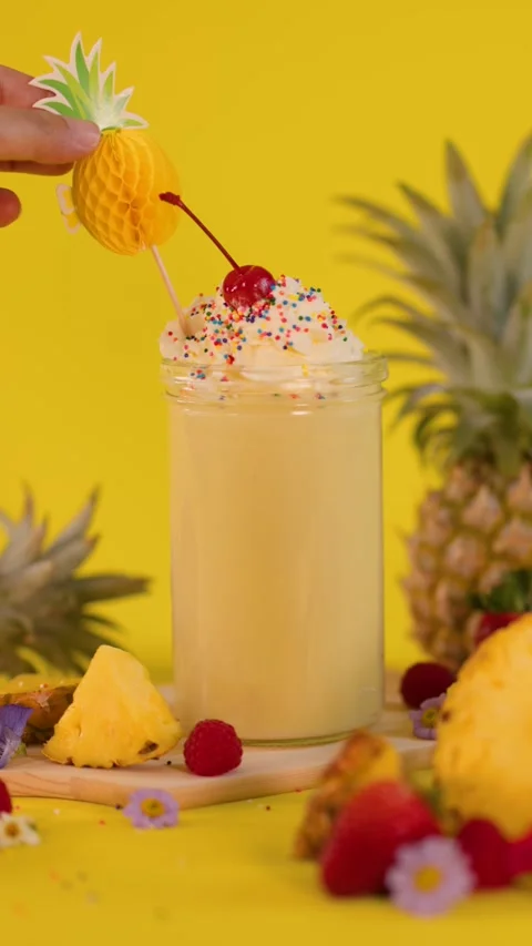 Hand Garnishing Pineapple Smoothie with Decorative Fruit Topper Stock Footage 322573152