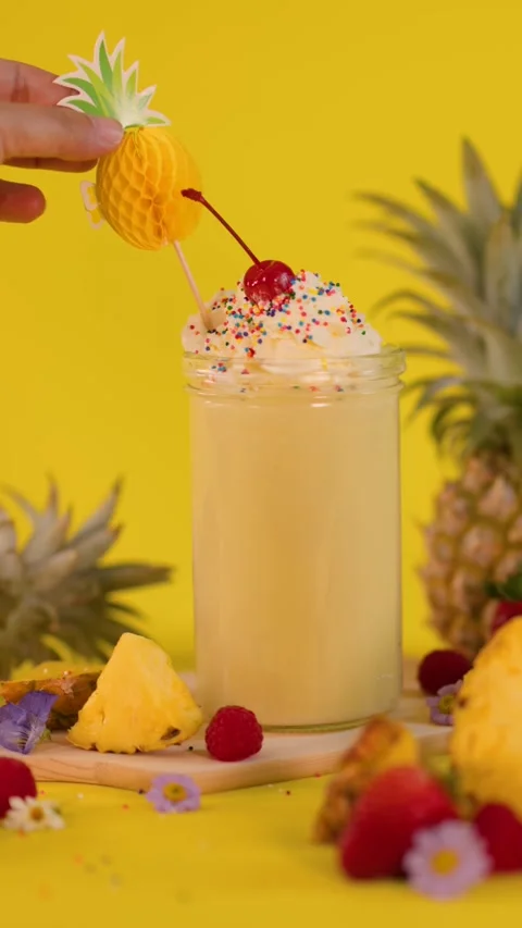 Hand Garnishing Pineapple Smoothie with Decorative Fruit Topper Stock Footage 322573198