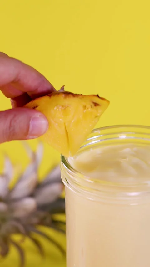 Hand Garnishing Pineapple Smoothie with Fresh Pineapple Slice Closeup 库存影片 323058347