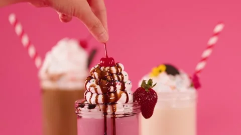 Hand Garnishing Strawberry Milkshake with Cherry and Chocolate Drizzle Stock Footage 321443664