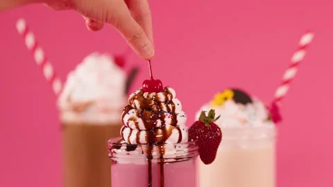 Hand Garnishing Strawberry Milkshake with Cherry and Chocolate Drizzle Stock Footage 321718822