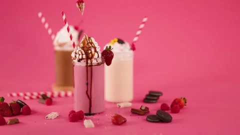 Hand Garnishing Strawberry Milkshake with Cherry and Whipped Cream Stock Footage 321850980