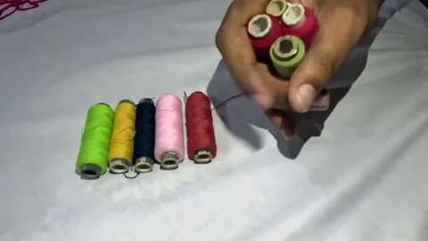 Hand Gathering Colorful Sewing Thread Spools on White Fabric 库存影片 341762478