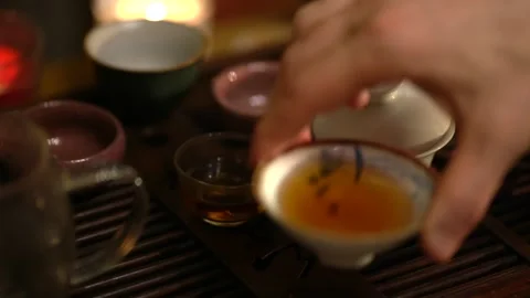 A hand gently holds a tea cup during a traditional Chinese tea ceremony at dusk Stock Footage 322611517