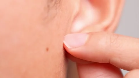 A hand gently massaging an earlobe conveys self-care. Video stock 317076068