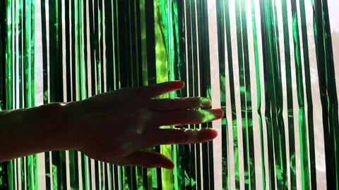 A hand gently reaches towards a shimmering, green curtain Stock Footage 258455409