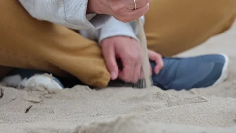 Hand gently sifting through soft sand, showcasing the delicate flow of grains in Stock-Footage 317041716