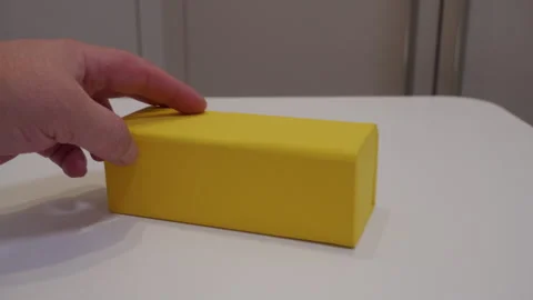 Hand Gently Slides Yellow Box Containing Glasses on Smooth Table. 库存影片 321437382