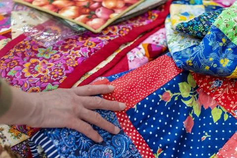 Hand gently touches bright patchwork quilt with lots of colorful floral and.. Stock Photos
