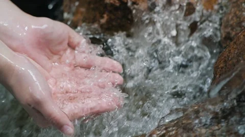 Hand gently touches the surface of the waterfall in the forest river or lake. Stock Footage 150473294