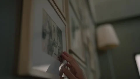 A hand gently touching old framed asian family photographs on the wall, Memories Stock Footage 328491405