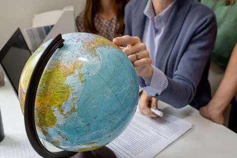 Hand of geography teacher pointing at continent on globe Stock Photos