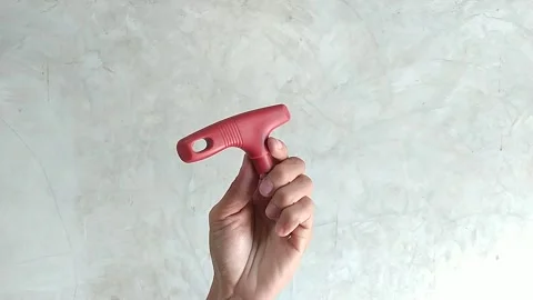 Hand gesture holding a red bottle cap puller Stock Footage 256349633