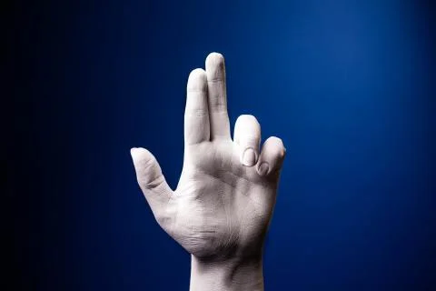 Hand gesture. Human gesture. Two fingers on a blue background. White hand in Stock Photos