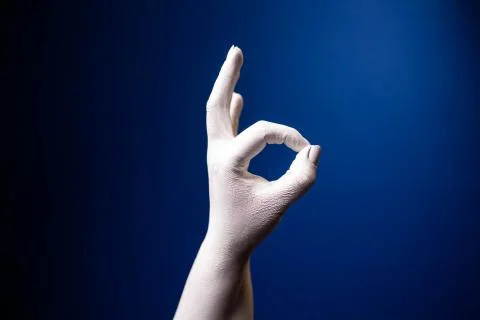 Hand gesture. Human gesture. Two fingers say OK on a blue background. White hand Foto stock
