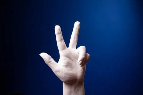 Hand gesture. Human gesture. Two fingers say hello on a blue background. White Stock Photos