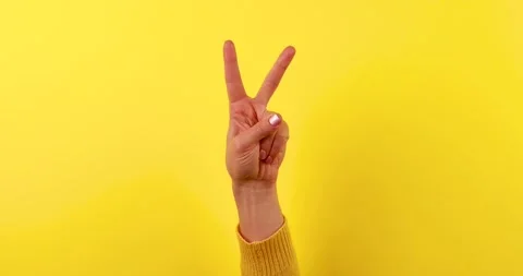 Hand Gesture V Sign for Victory or Peace on Yellow Background Stock Footage 324855293