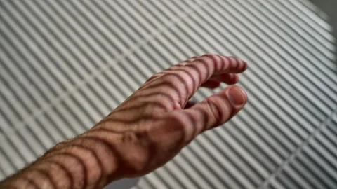 Hand gestures with line pattern from sunlight from window shutters blinds Stock Footage 311709724