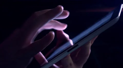 Hand gestures over tablet computer in dark room. Purple glowing touchscreen 4K Stock Footage 68919261