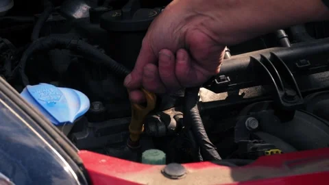 Hand gets engine oil dipstick and screenwash tank in car Video stock 344747195