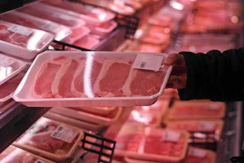 A hand getting a pack of pork at the meat corner of a supermarket.  Stock Photos