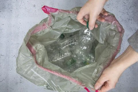 Hand getting plastic bottles to dispose in garbage bag ready to recycle, waste Stock Photos