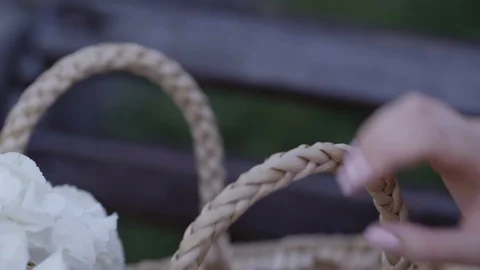 A hand of a girl is puting down a whicker bag with flowers, close up Stock Footage 96065427