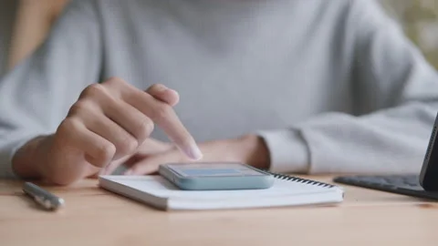 Hand of a girl texting using the mobile phone on the desk in the morning Stock Footage 137861771