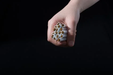 Hand is giving out bundle of cigarettes on black Stock Photos