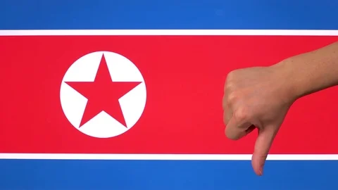 Hand giving thumb down with North Korea flag disapproval gesture with copy space Видео 84785392