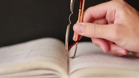 Hand with glasses over a book Stock Footage 75628912