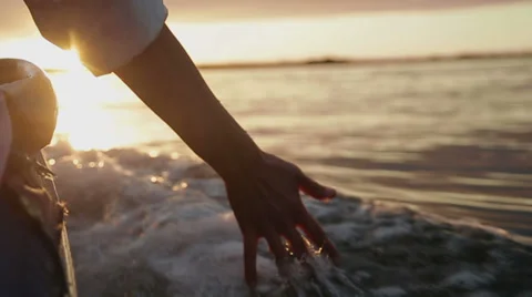 Hand glides over waves at sunset Stock Footage 28739766