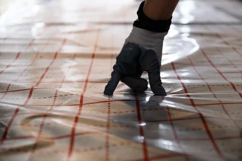 Hand in glove checking the underfloor heating foil Stock Photos