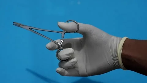 Hand with glove hold surgical forceps on blue background. Surgery instrument Stock Footage 309239074