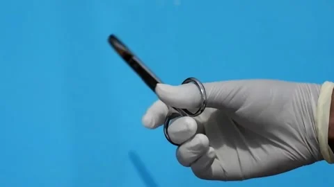 Hand with glove hold surgical scissors on blue background. Surgery instrument Stock Footage 309239087