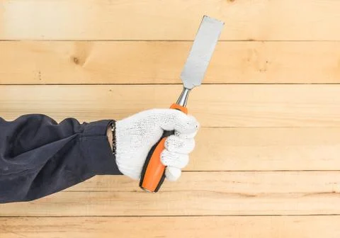 Hand in glove holding chisel Foto stock
