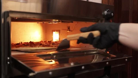 A hand in a glove opens a grill door revealing cooking meats glowing in the Stock Footage 304457659