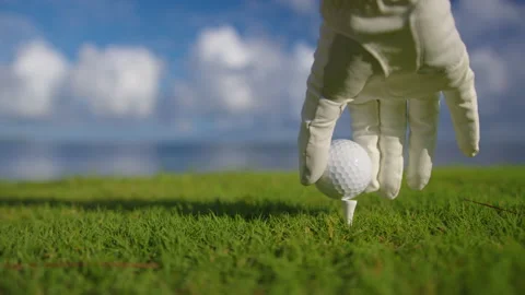 Hand in glove placing golf ball on tee Stock Footage 172545205