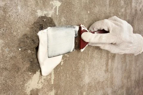 Hand in glove plastering surface of wall with spatula Stock Photos