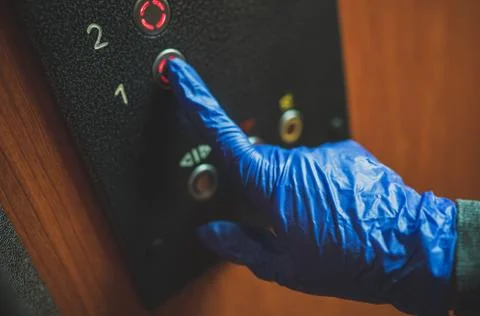 Hand in glove pressing the elevator button. Fotos de archivo