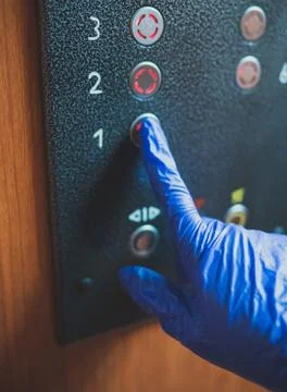 Hand in glove pressing the elevator button. Fotos de archivo