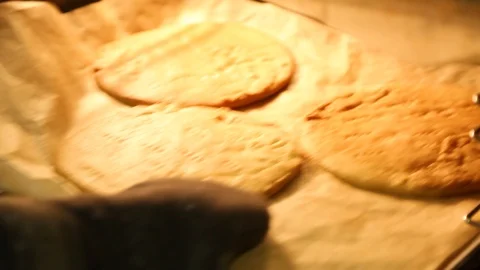 Hand in glove pulls out of the oven, three flatbreads on two trays Stock Footage 107715479
