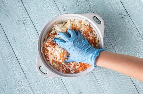 Hand in glove squeezing grated cabbage and carrot Stock Photos