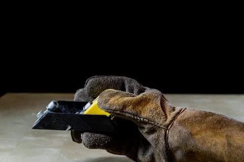 Hand in glove with tool for work in workshop. Hand protected by working coat. Stock Photos
